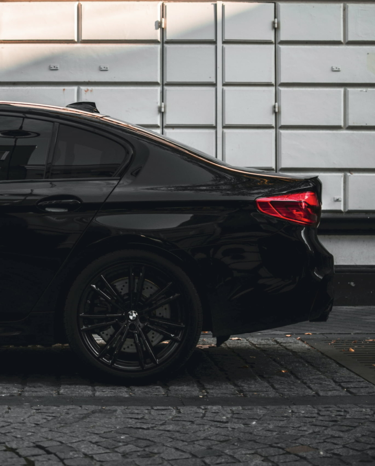 A black BMW with tinted windows and black alloys